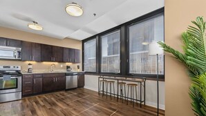A modern kitchen with dark cabinets, a microwave, a stove, and a bar area with stools.
