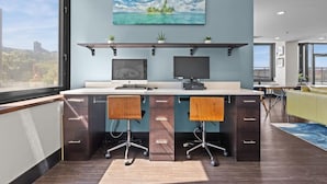 A modern office space with a large desk, two chairs, and a view of a cityscape through large windows.