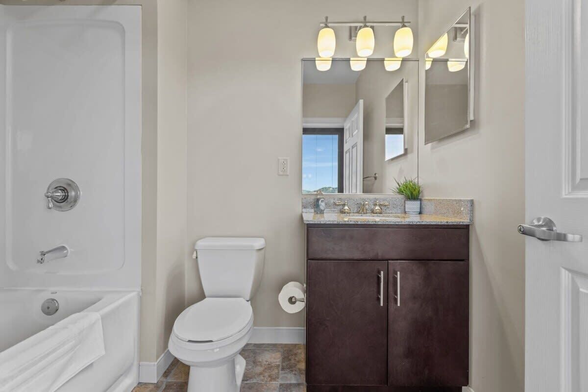 A bathroom with a white toilet, dark brown cabinet, and a countertop with a plant.