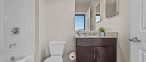 A bathroom with a white toilet, dark brown cabinet, and a countertop with a plant.