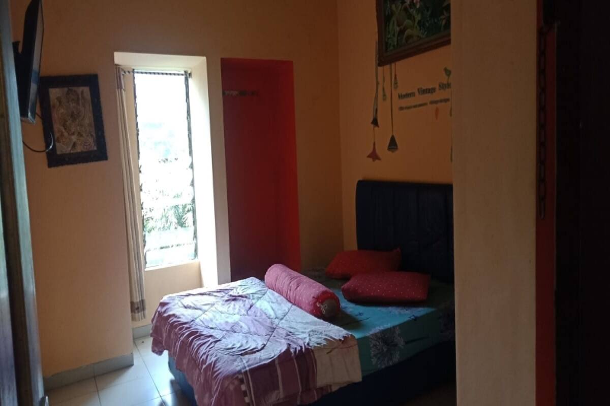 A bedroom with a bed, a window with curtains, and a wall-mounted sign.