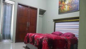 A bedroom with a bed, a wooden wardrobe, a painting on the wall, and a window with curtains. - OYO Life 90646 Villa Karsinem Pasuruan (Prigen)