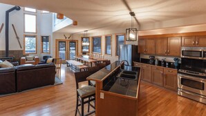 Una cocina moderna con armarios de madera, una isla central con pileta y un área de comedor con sofá y sillas.