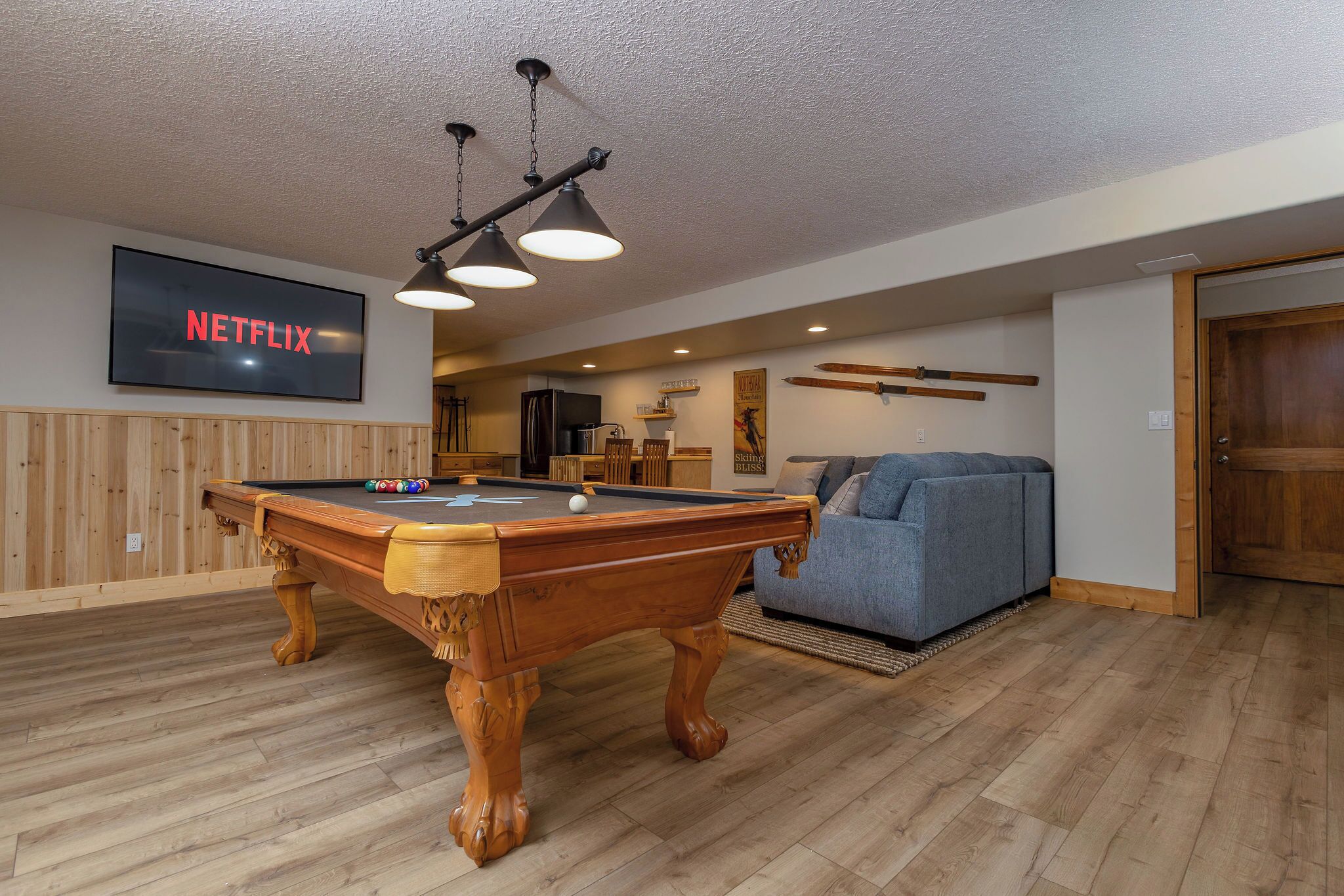 A pool table with a Netflix sign, a sofa, and a wooden door.