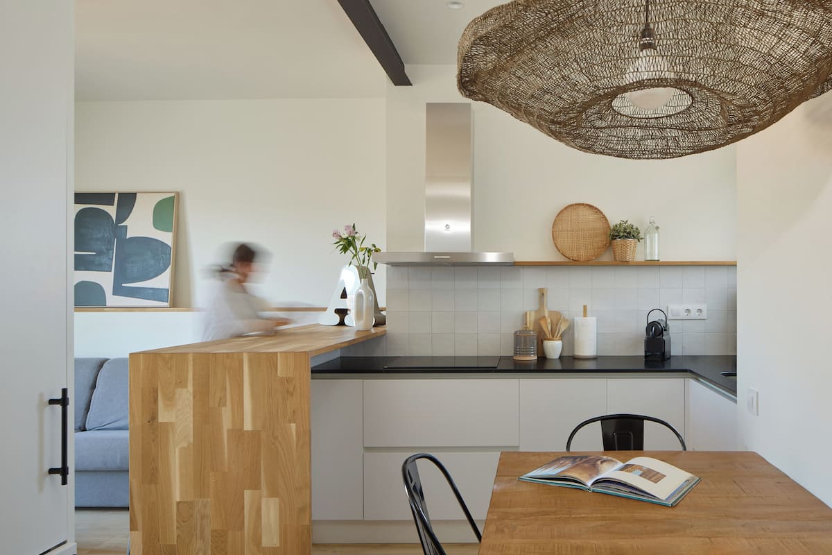 A modern kitchen with a wooden island, white cabinets, and a black countertop.