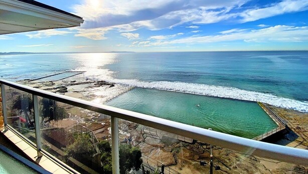 A view from a balcony overlooking a beach with a swimming pool and rocky terrain. - Gobsmacking Views 6 with Direct Beach Access (Cronulla)