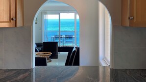 A kitchen with a view of the ocean through an archway. - Gobsmacking Views 6 with Direct Beach Access (Cronulla)