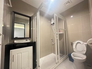A modern bathroom with a glass shower enclosure, a toilet, and a vanity with a mirror. - Metro Link Ratchada Hotel (Bangkok)