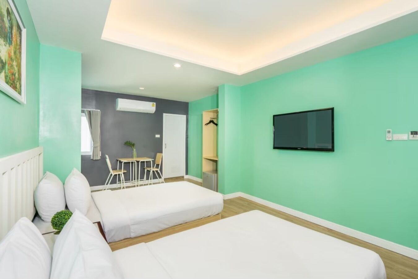 Una habitación de hotel con dos camas, un televisor y un comedor con sillas y una mesa.