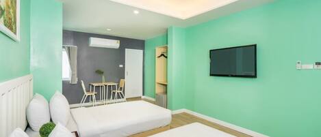 Una habitación de hotel con dos camas, un televisor y un comedor con sillas y una mesa.