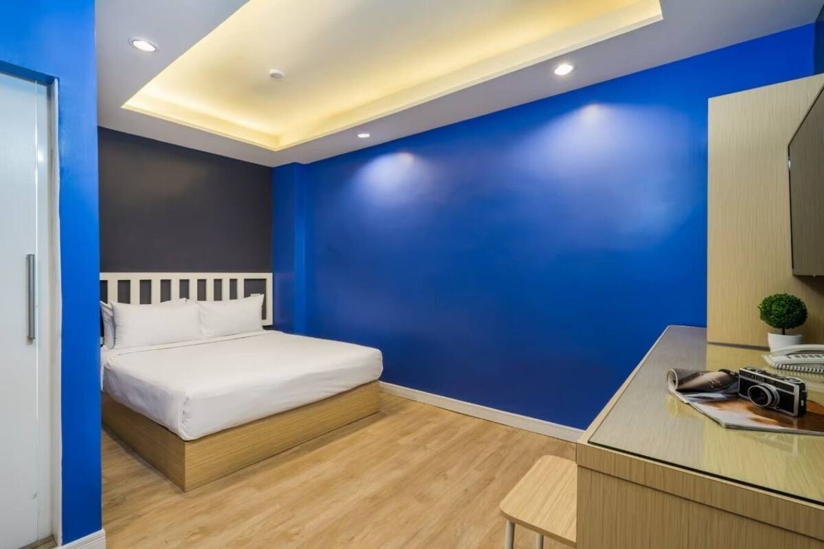 Quarto moderno com cama, escrivaninha e uma pequena planta.