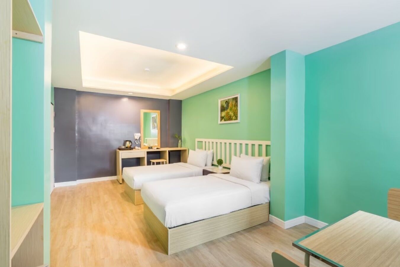 Una habitación de hotel con dos camas, un escritorio, un espejo y una lámpara en el techo.
