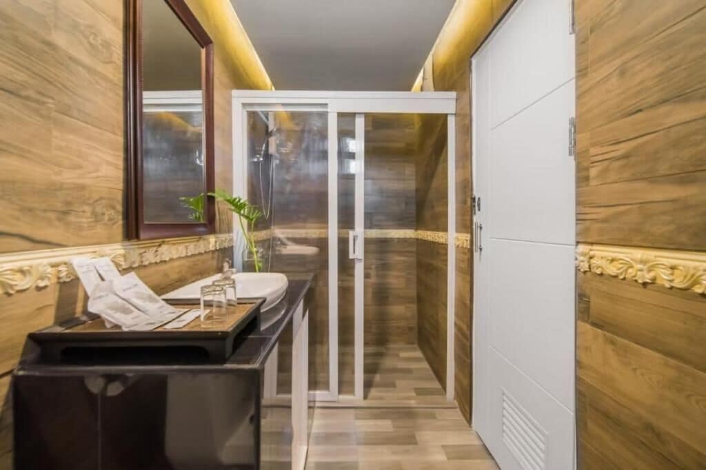 A modern bathroom with a wooden wall, a glass shower enclosure, and a vanity with a sink and mirror.