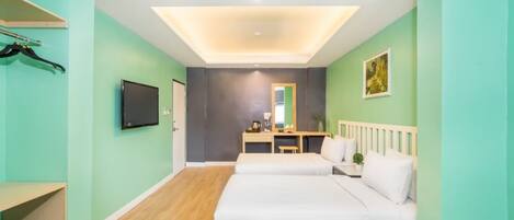 Een hotelkamer met twee bedden, een bureau, een spiegel, een televisie en een plafondlamp.