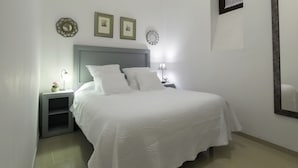 A neatly arranged bedroom with a bed, bedside tables, and wall decorations. - Apartamento Estándar (Sevilla)