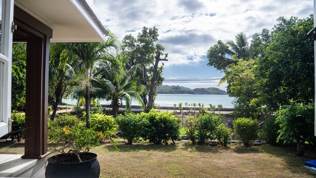 A view from a balcony overlooking a beach with palm trees and a clear sky. - Anse Boudin Villa (Praslin)