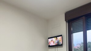Zona pranzo con tavolo e sedie, televisore montato a parete e vista attraverso una porta in vetro.