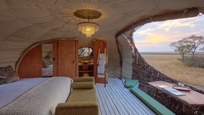 Un hébergement sous tente comprenant un lit, un coin salon, une table et une vue sur le paysage.