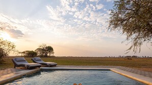 Un espace aménagé au bord de la piscine, avec des chaises longues et un plateau de boissons.