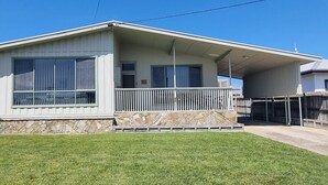 A single-story house with a stone foundation, a covered porch, and a fenced backyard.