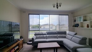 A living room with a sectional sofa, a television, a coffee table, and a bookshelf.
