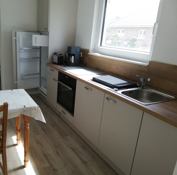 A small kitchen with a window, a sink, a toaster, and a coffee maker. - Ferienwohnung Amunds Koje Plus, Kinder-und Hundefreundl., Nähe Strand u Zentrum (Butjadingen)