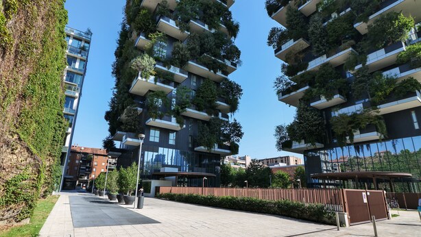 A modern high-rise building with balconies covered in greenery, a paved walkway, and a clear blue sky. - Luxury Suite in bosco Verticale Milano Isola  (Milano)
