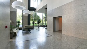 A spacious lobby with a modern design, featuring a seating area with sofas and a coffee table, large windows providing natural light, and a clean, polished floor. - Luxury Suite in bosco Verticale Milano Isola  (Milano)