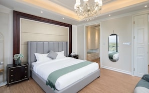 Une chambre à coucher moderne avec un grand lit, une table de chevet, une commode et un lustre.