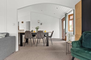 Un intérieur moderne comprenant un coin repas, un canapé et un fauteuil vert.