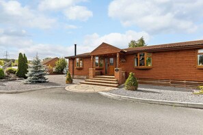 Une cabane en bois avec une entrée en pierre, une cheminée et une allée gravillonnée.