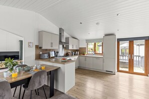 Une cuisine moderne avec des meubles blancs, un coin repas avec une table mise pour le petit-déjeuner et une grande fenêtre donnant sur une terrasse.