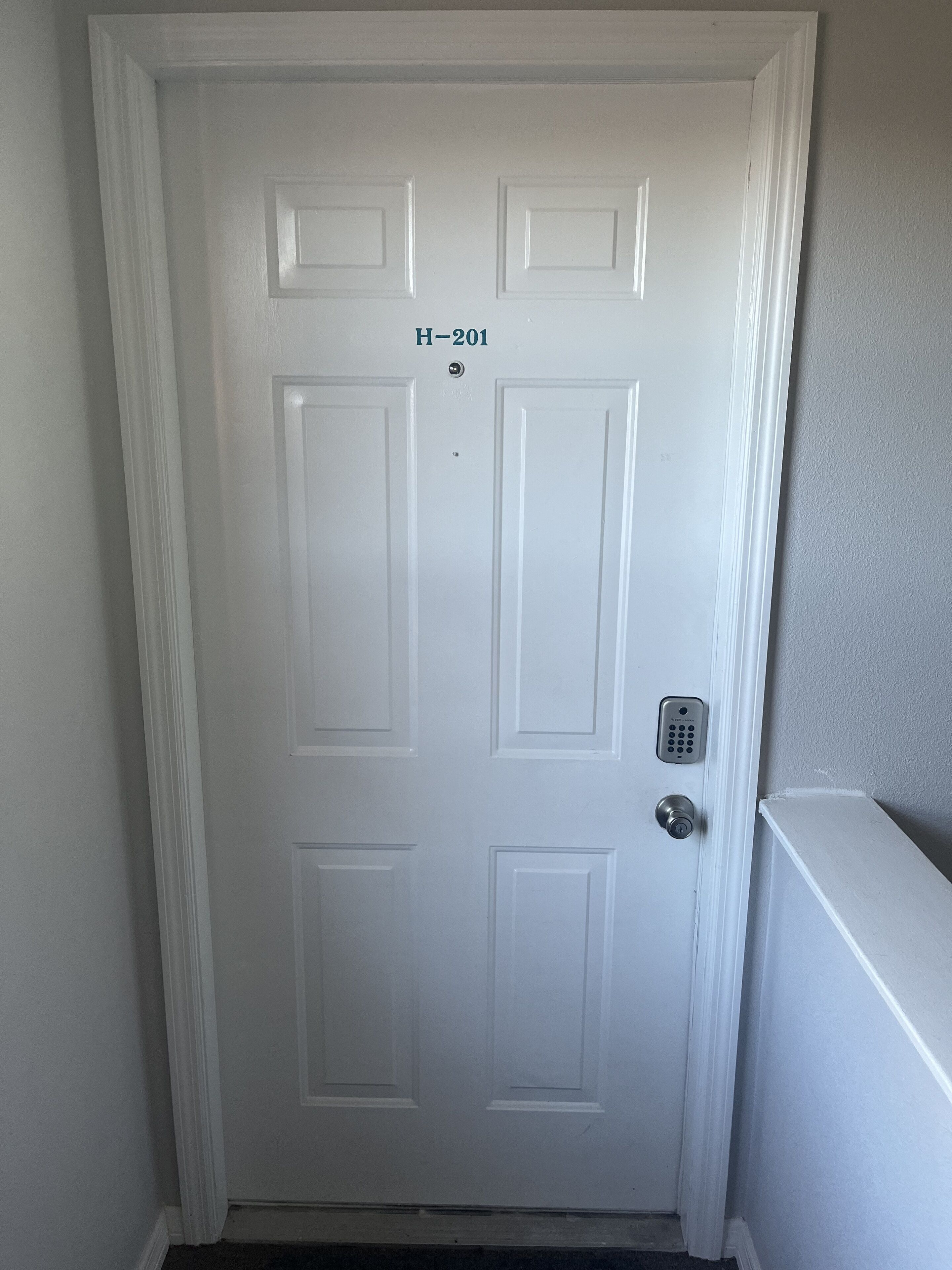 A white door with a numeric keypad lock labeled "H-201".