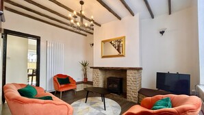 Ein Wohnzimmer mit zwei orangefarbenen Sesseln, einem Kamin, einem Fernseher und einer Deckenleuchte.