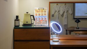 Un bureau en bois avec une bouilloire, un tableau affichant le menu, un anneau lumineux et une bouteille de gel hydroalcoolique.
