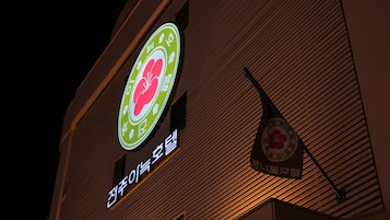 A building with a sign featuring a green and white logo with a red flower, and Korean text.