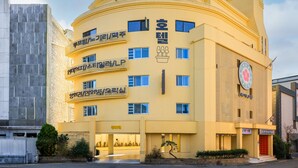 Un bâtiment jaune doté de nombreuses fenêtres et de balcons, avec une enseigne en langue étrangère.