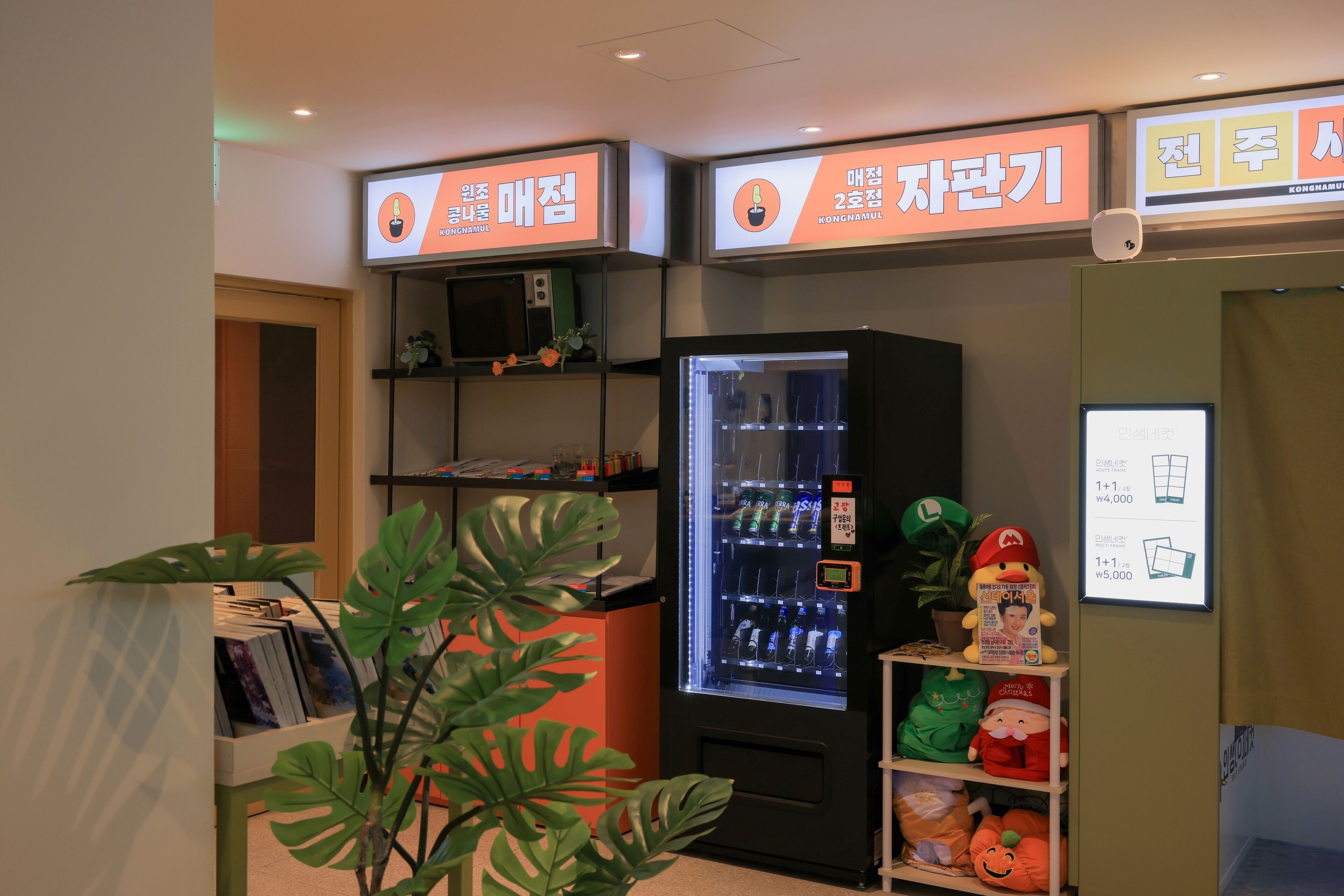 A vending machine with drinks, a small display with a plant, and a shelf with plush toys.
