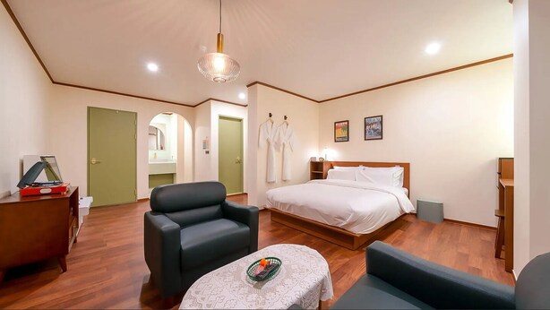 Une chambre d’hôtel comprenant un lit, une chaise, une petite table avec un panier, un bureau avec une platine vinyle et un miroir.