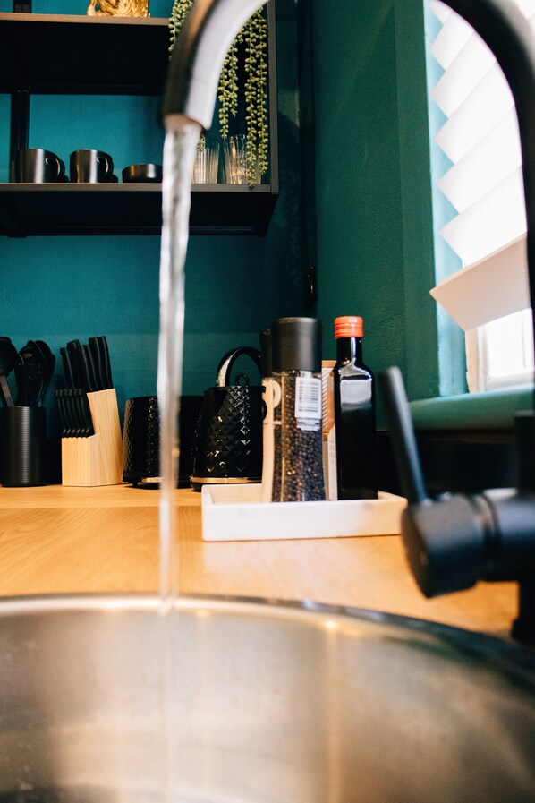 Un évier de cuisine avec l’eau courante, un bloc à couteaux et divers ustensiles de cuisine.