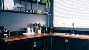 A modern kitchen with a wooden countertop, black cabinets, a built-in oven, and a window with blinds.