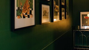 A hallway with framed artwork on the walls, a patterned floor, and a bar area with a counter and chairs.