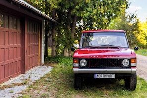 A red Range Rover parked in front of a red garage.