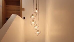 A modern staircase with a geometric light fixture and a wooden door at the top.