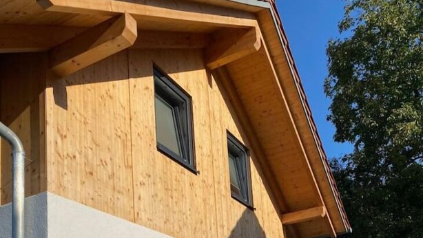 A modern building with a wooden facade and a white lower section. There are steps leading to a seating area with outdoor furniture. - holiday flat "Felina" (Passau)