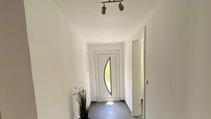A hallway with a plant, a door with a unique design, and a ceiling light fixture. - holiday flat "Felina" (Passau)