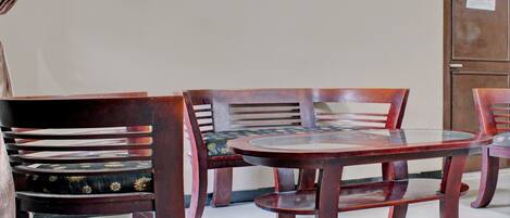 A dining area with a round table and wooden chairs with cushioned seats.