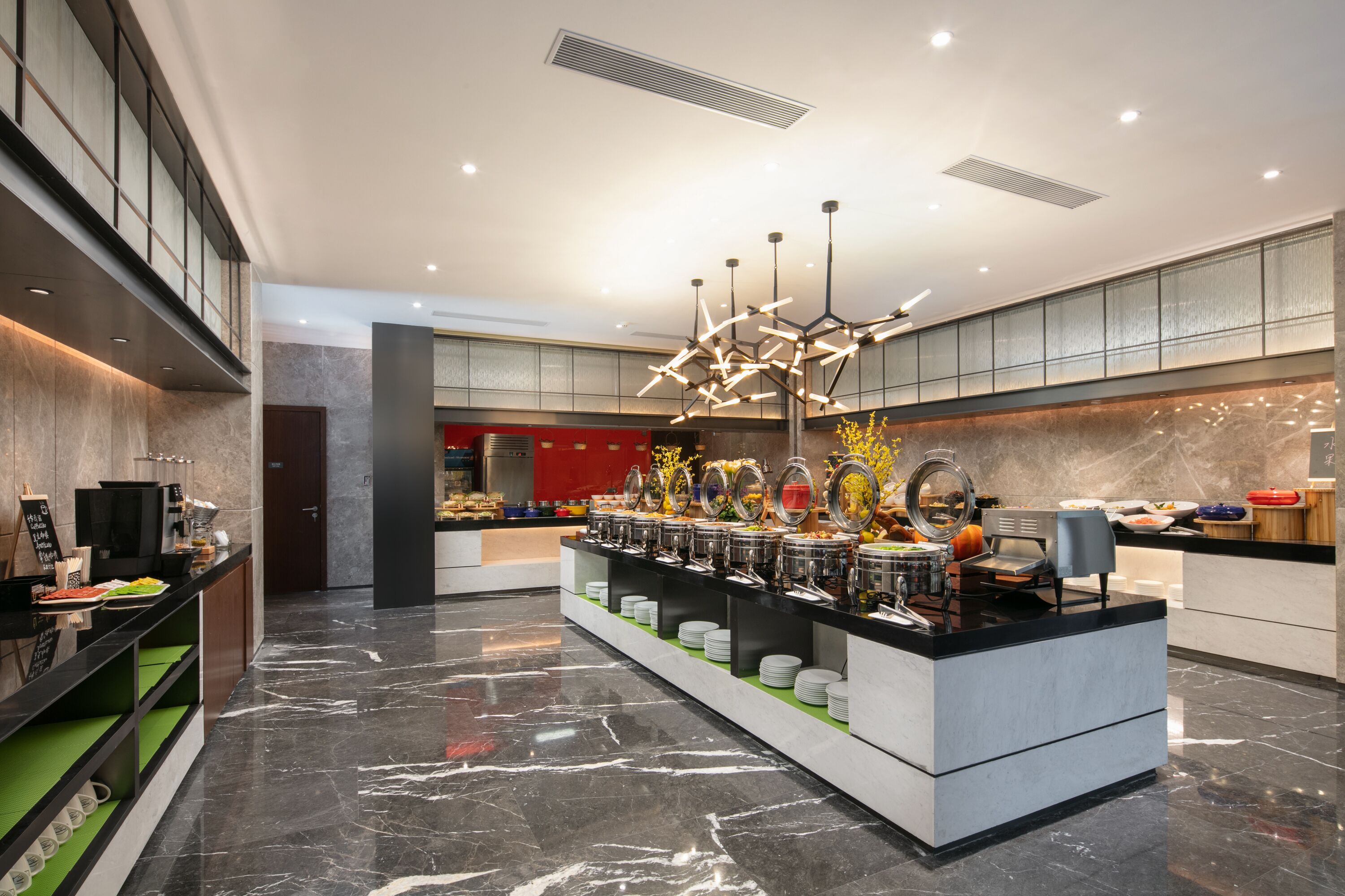 A modern hotel lobby with a buffet area, marble flooring, and contemporary lighting fixtures.