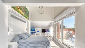Un dormitorio moderno con una cama grande, un ventilador de techo y vistas al balcón exterior.