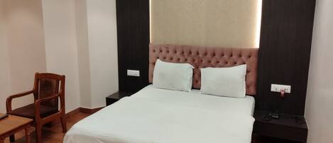 Un dormitorio ordenado con una cama grande, una silla de madera y una mesita de noche.